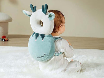 A baby wearing a teal colour backpack style head protector