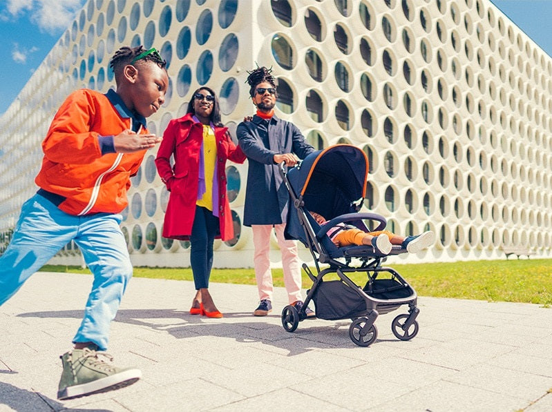An image of a family with a compact stroller on-the-go. Children happily explore their surroundings, making cherished memories.
