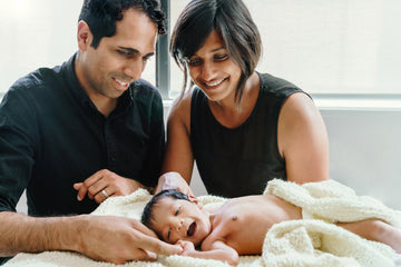 Image contains a newborn with happy parents
