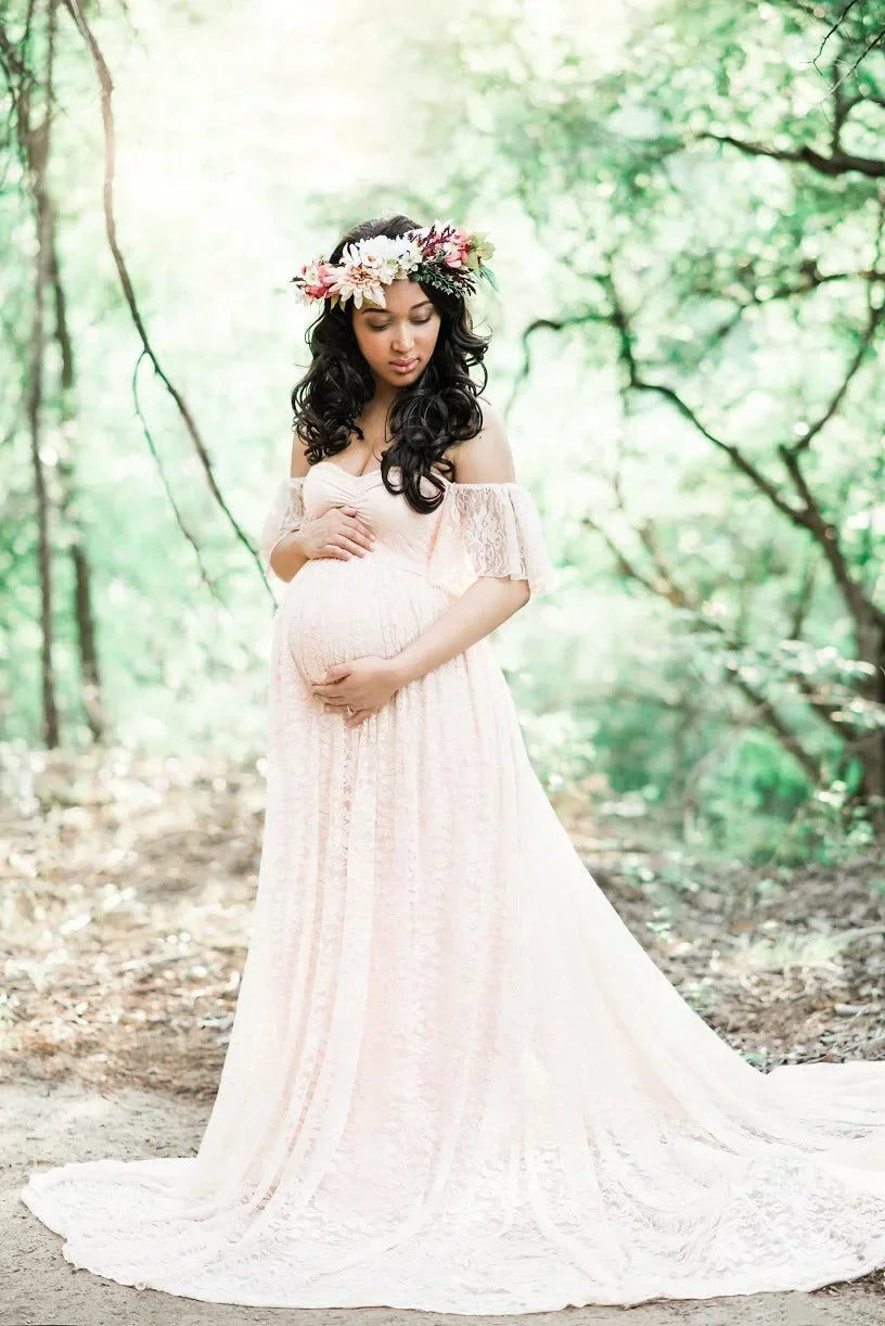 Pregnant woman in a flowing white dress standing in a forest