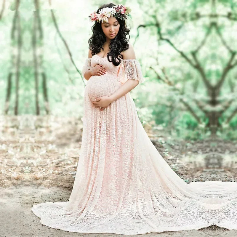 Pregnant woman in a pink lace dress standing in a forest